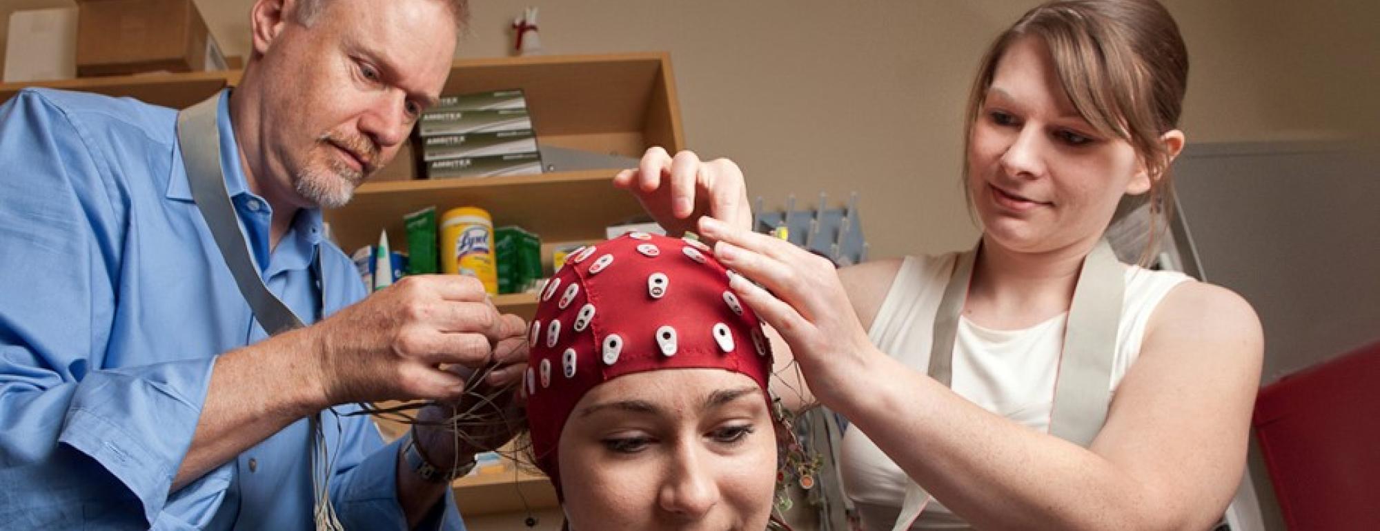 professor and researcher applying EEG leads to a research participant