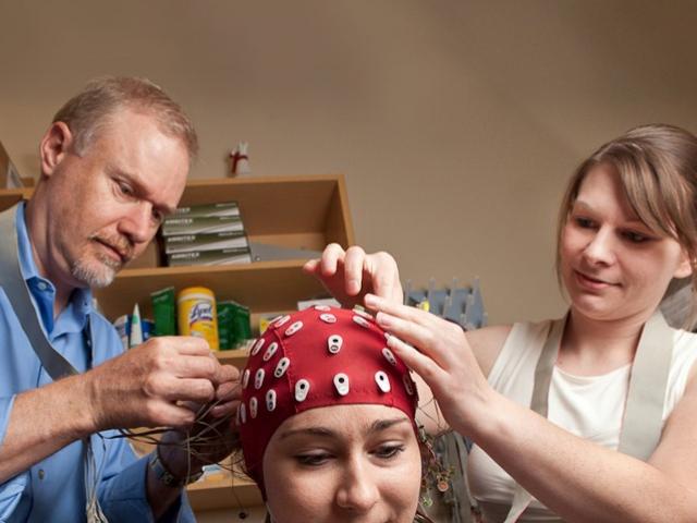 professor and researcher applying EEG leads to a research participant