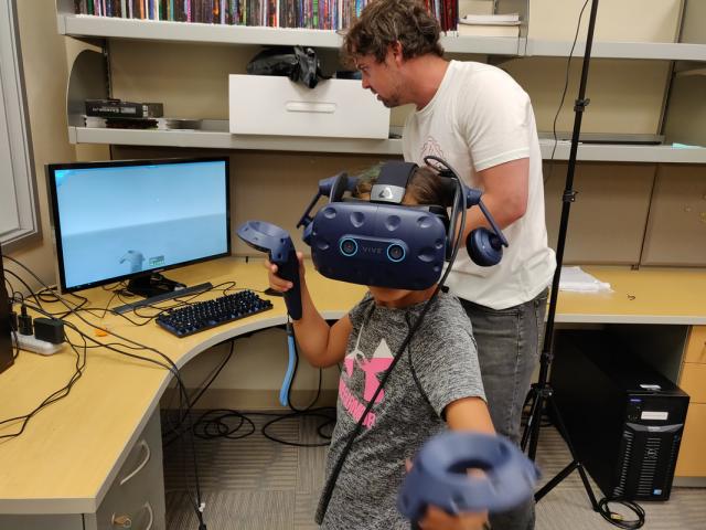 researcher with a child who is using virtual reality gear