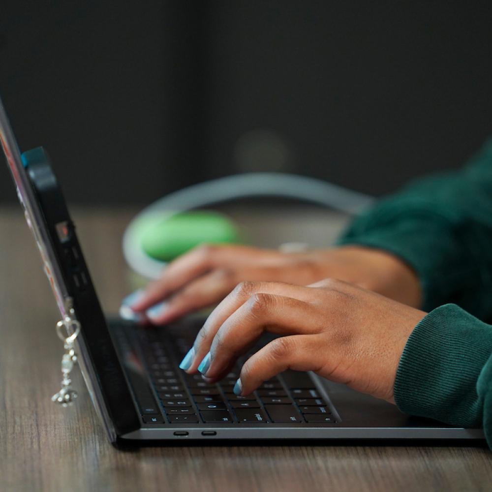 Hands typing on a laptop