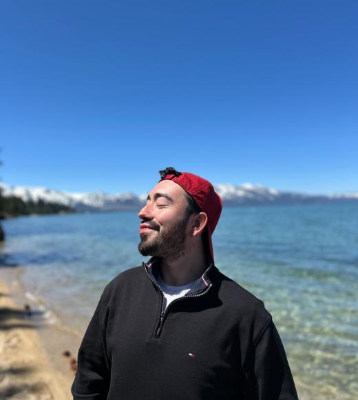 An image of Sebastian standing in front of a lakeview.