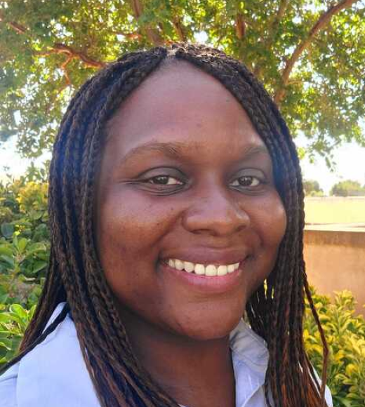 a woman smiling with braids and a white shirt