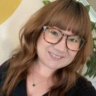 A woman with red hair and glasses wearing a black shirt