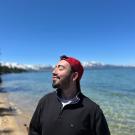 An image of Sebastian standing in front of a lakeview.