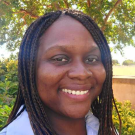 a woman smiling with braids and a white shirt